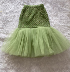 Green sequin top and tulle skirt set on a fluffy gray surface